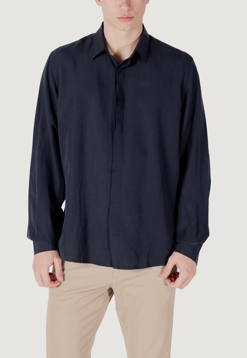 Marineblauwe longsleeve shirt van lichtgewicht stof, met een button-down voorkant en een relaxte pasvorm, gecombineerd met beige broeken.