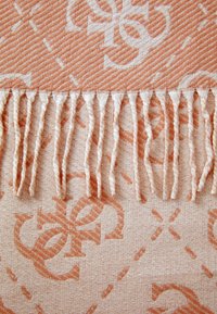 Peach patterned fabric with a textured finish, featuring a subtle design and fringed edges for a decorative touch.