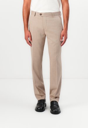 Pantalons habillés beiges avec une finition texturée, coupe droite et fermeture à un bouton, accompagnés de chaussures noires à enfiler.