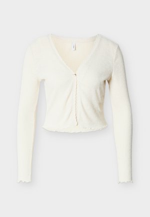 Witte geribbelde cropped cardigan met lange mouwen, een V-hals en een golvende zoom. Voorzien van een enkele knoopsluiting aan de voorkant. Zachte textuur.