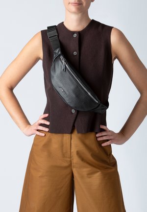 Schwarze Leder-Umhängetasche mit strukturiertem Finish, schlanker Form und kantigem Design. Mit einem Reißverschluss und einem verstellbaren Tragegurt für zusätzlichen Komfort.