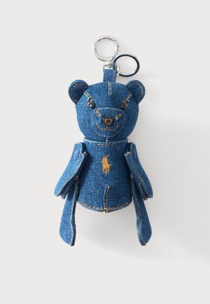 Porte-clés ours en denim avec logo polo brodé, yeux boutons noirs, membres mobiles et anneaux de clé argentés sur fond blanc.