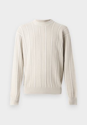 Pull en tricot crème avec une texture à côtes verticales, col rond et manches longues. La coupe est décontractée avec des finitions côtelées aux poignets et à l'ourlet.