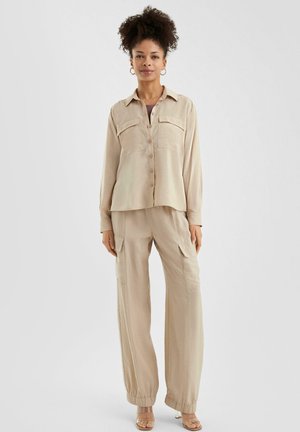 Beige, long-sleeve button-up shirt with two chest pockets paired with matching wide-leg cargo pants; lightweight fabric with a smooth texture.