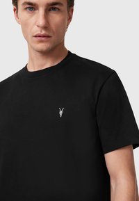 T-shirt di cotone nero con collo a giro, maniche corte e una piccola ricamatura di teschio di capra argentato sul lato sinistro del petto.
