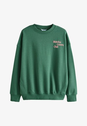 Bluza verde cu decolteu rotund și mâneci striate, cu broderie roz „Matcha Lovers Club" pe față. Textură moale, croială lejeră.
