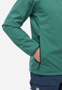 Veste softshell verte avec une texture lisse et une poche latérale zippée, dotée d'une conception de manches ajustées et d'une doublure contrastante.