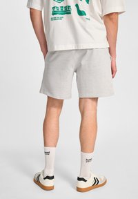 Lichtgrijze shorts van zachte stof, met een casual pasvorm. Draag ze met witte enkelsokken en lage sneakers met zwarte accenten.