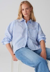 Camicia a righe blu chiaro e bianca con taschino sul petto e maniche arrotolate, realizzata in un tessuto morbido con una vestibilità comoda.