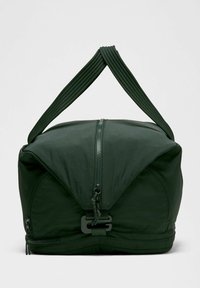 Zielona torba sportowa z zamkiem błyskawicznym, żebrowanymi uchwytami oraz unikalnym składającym się wzorem. Posiada gładką fakturę i minimalne detale.