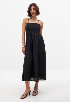Schwarzes, ärmelloses Maxikleid mit geradem Ausschnitt, gerafftem Taillenbund und fließendem Rock. Glattes Material mit weicher Textur.