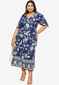 Marineblauwe bloemenjurk met een V-hals, korte pofmouwen, een elastische taille en witte bloemenpatronen. Voorzien van een gedecoreerde zoom en een vloeiende silhouet.