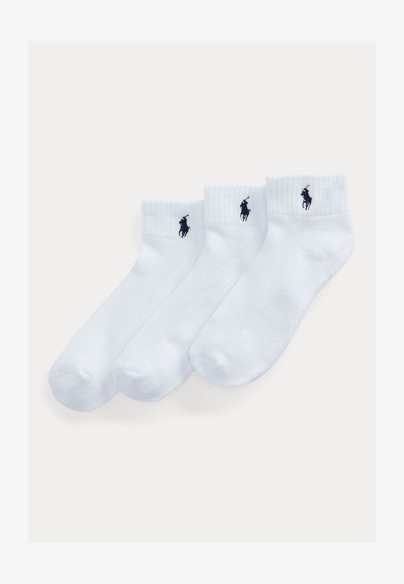 Tre par hvide ankelsokker med sorte polo-spiller logoer på ribstrikkede kanter, arrangeret på en ensfarvet lys baggrund.