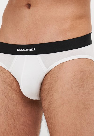 Culotte blanche en coton avec une taille noire portant le texte "DSQUARED2" en blanc. Le design comprend des détails de couture et est ajusté.