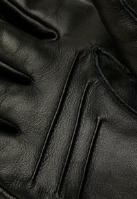 Schwarze Lederhandschuhe mit einer weichen Textur, ausgeprägten Nähmustern und hervorgehobenen Nähten für zusätzlichen Halt und Stil.