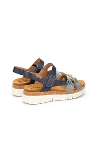 Sandalias con suela de corcho que presentan tiras de cuero en tonos azul marino y azul claro, con la parte trasera abierta y acentos texturizados. Livianas, con una gruesa suela blanca.