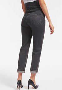 Jean taille haute, gris foncé, avec des poignets roulés, présentant un design à cinq poches et un détail de logo distinctif sur la poche arrière.