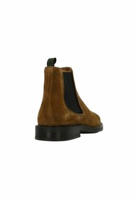 Bruine suede Chelsea-boots met elastische zijpanelen, een ronde neus en een zwarte rubberen zool. Inclusief een groene lus aan de achterkant voor gemakkelijk aan- en uittrekken.