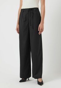 Zwarte streepbroek met een ontspannen pasvorm, een trekkoord in de taille en wijde benen. De stof lijkt glad met op maat gemaakte accenten.