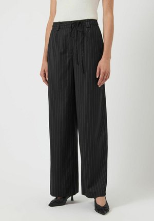 Zwarte streepbroek met een ontspannen pasvorm, een trekkoord in de taille en wijde benen. De stof lijkt glad met op maat gemaakte accenten.