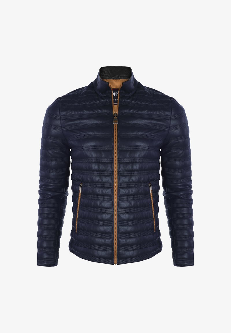 Veste matelassée bleu marine avec coutures horizontales, fermeture éclair et bordure marron, col montant et poches latérales zippées.