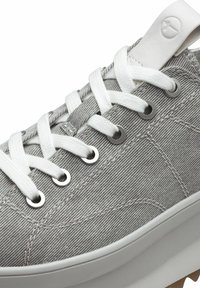 Grå canvas sneakers med vita snören och metallöglor. Har en texturerad yta och en vit gummisula med en lätt klack.