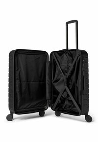 Valise rigide noire à coque texturée, ouverte pour révéler un intérieur noir uni et des sangles ajustables pour sécuriser les objets.