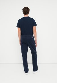 Donkerblauw katoenen T-shirt gecombineerd met donkerblauwe broek. De broek heeft achterzakken en een klein logo-accent; beide hebben een comfortabele pasvorm.