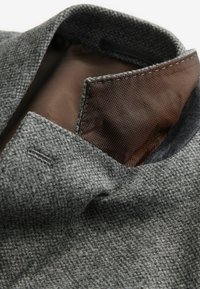Col roulé en tissu texturé gris avec une doublure marron. Présente de belles coutures et une finition intérieure lisse, mettant en avant un design soigné.