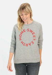 Grijze sweatshirt met rode cirkelvormige tekst die "HOME SWEET EARTH" leest. Zachte stof met ribgebreide manchetten en zoom, ontspannen pasvorm.