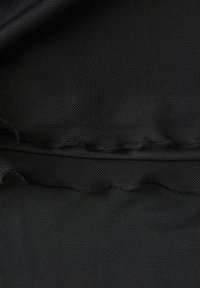 Tessuto nero con una superficie testurizzata, caratterizzato da un riflesso fine a rete e un bordo arricciato lungo la cucitura. Materiale morbido e leggero.
