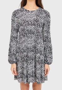 Robe à manches longues en imprimé animal noir et blanc, dotée d'un col rond et d'une jupe à volants avec une texture froncée.