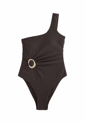 Nahaufnahme des oberen Rückens einer Person, die ein braunes, strukturiertes ärmelloses Oberteil mit kleinem Metalllogo und sichtbarem dunklem Muttermal auf der Haut trägt.