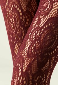 Collants en dentelle bordeaux avec un motif floral, ornés de découpes complexes, d'une texture douce et d'une coupe près du corps.