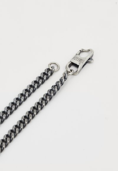 Silverfärgad hundkoppel i metall med flätad kedja, utrustad med en robust krok och cirkulär ringfäste. Slät, polerad yta.