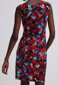 Eng anliegendes ärmelloses Kleid mit einem mehrfarbigen Patchwork-Muster in den Farben Rot, Blau, Grün und Schwarz mit glatter Textur.