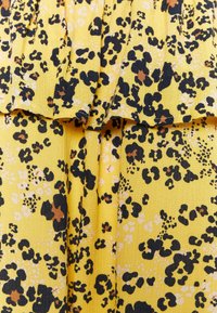 Tissu jaune avec un design texturé plissé comportant des taches de léopard noires et brunes ainsi que des motifs abstraits blancs.