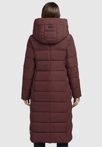 Bordeaux pufferjas, tot de knie, met een grote capuchon, doorgestikte afwerking en zijzakken. De stof lijkt glad met een matte afwerking.