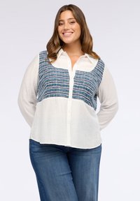 Camicia button-up con un motivo intrecciato blu e bianco nella parte superiore e una parte inferiore bianca uniforme, con maniche lunghe e colletto classico.