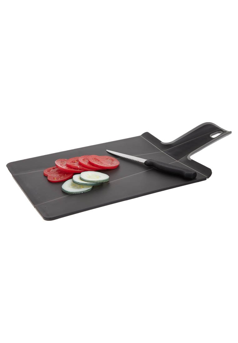 Zwarte plastic snijplank met een handvat, met gesneden tomaten en komkommers, vergezeld van een gekarteld mes dat op het oppervlak is geplaatst.