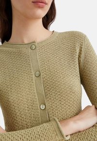 Cardigan lavorato a maglia verde oliva con un motivo testurizzato, dotato di scollatura rotonda e tre bottoni sulla parte anteriore.