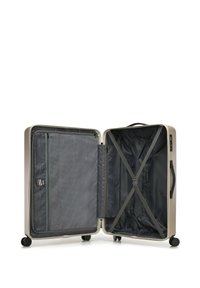 Twarda walizka o metalicznym beżowym wykończeniu, z wyściełanym wnętrzem, pasami kompresyjnymi i zapinaną na zamek siateczkową kieszenią.