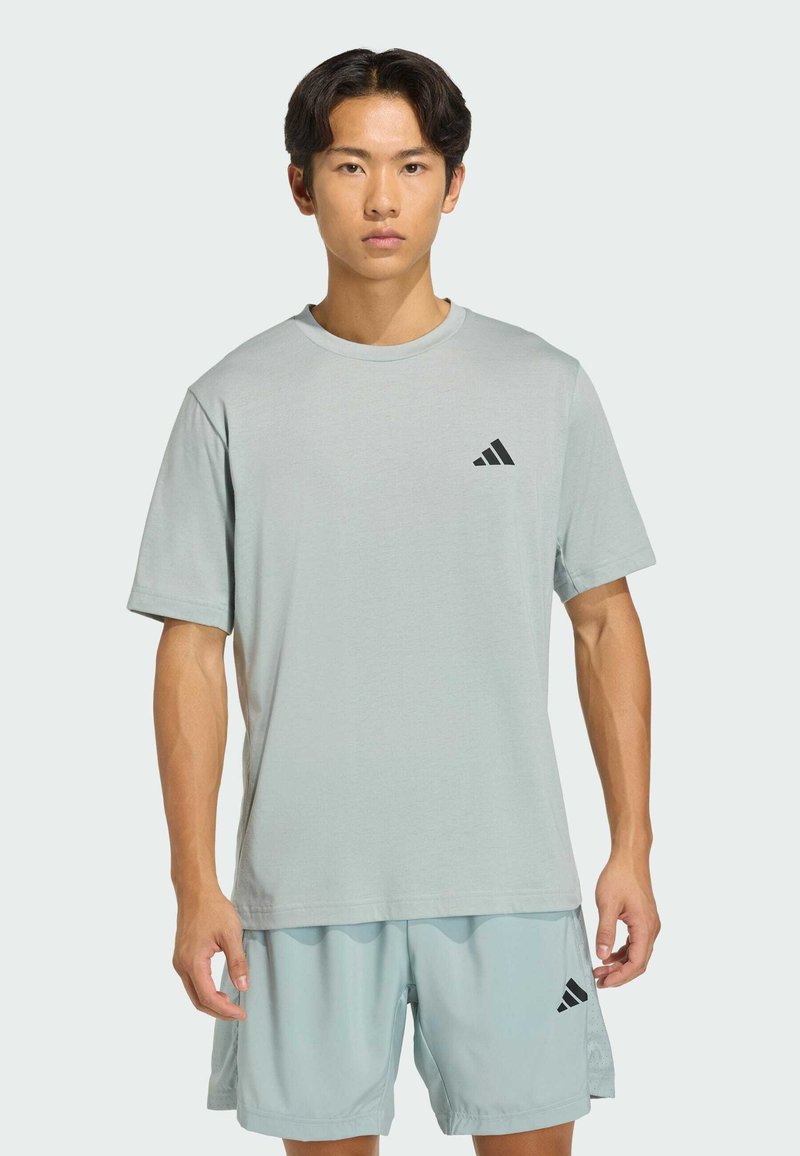 Svetlomodré atletické tričko s krátkymi rukávmi a okrúhlym výstrihom. Na ľavej strane na hrudi je čierne logo Adidas. Jemná textúra tkaniny.