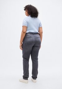 Ανοιχτό μπλε, υφασμάτινο πουκάμισο με κοντά μανίκια, συνδυασμένο με σκούρα γκρι τζιν. Τζιν σε χαλαρή εφαρμογή με δύο πίσω τσέπες και γυρισμένα μανίκια.