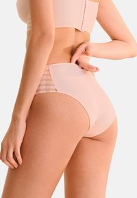 Culotte taille haute rose clair, avec un panneau en maille à motif quadrillé sur les côtés et une texture lisse côtelée sur l'ensemble.