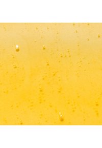 Un liquide jaune avec des bulles, présentant une texture lisse et une légère translucidité, créant une surface vibrante et uniforme.
