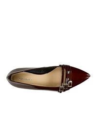 Scarpa in vernice bordeaux con punta a punta, dotata di tre fibbie metalliche sul cinturino e una soletta liscia beige. Silhouette pulita e finitura lucida.