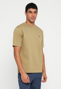 Krótki rękaw khaki t-shirt wykonany z bawełny, z okrągłym dekoltem i subtelnym logo na piersi. Miękka faktura i luźny krój.