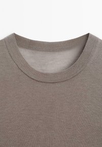 Zbliżenie na sweter w odcieniu taupe z okrągłym dekoltem, z widocznym ribbami przy kołnierzu oraz gładką teksturą dzianiny.