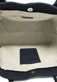 Borsa tote in pelle di un elegante blu scuro con interno color crema. Presenta una tasca con zip, uno slot per carte e una chiusura a scatto magnetico.